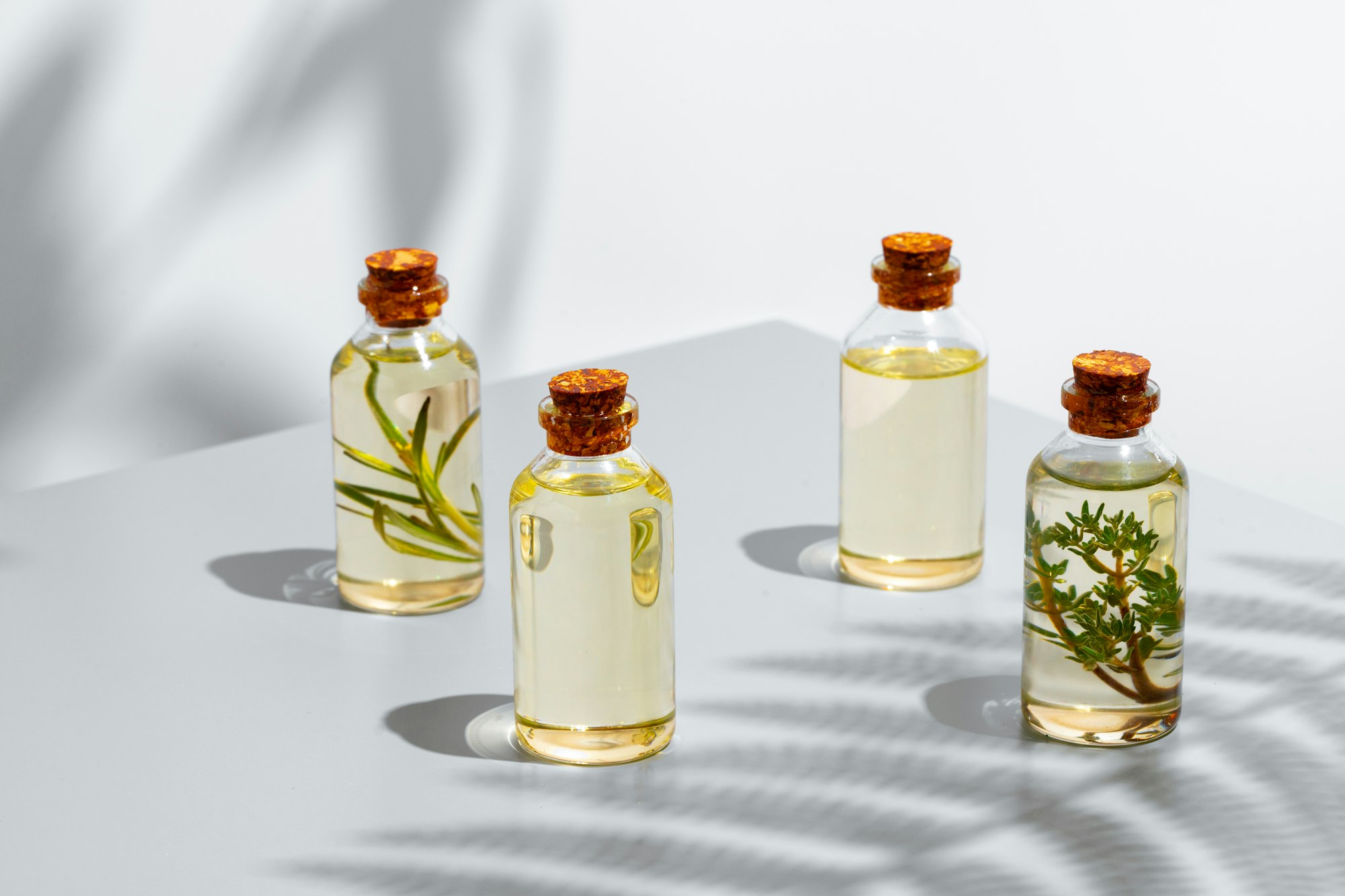 Bottle of essential oil with herbs on gray background